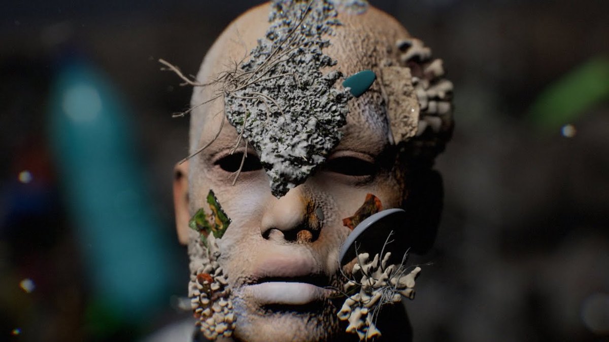 Still from Plaid’s Dancers video: a CG face overgrown with lichen and coral