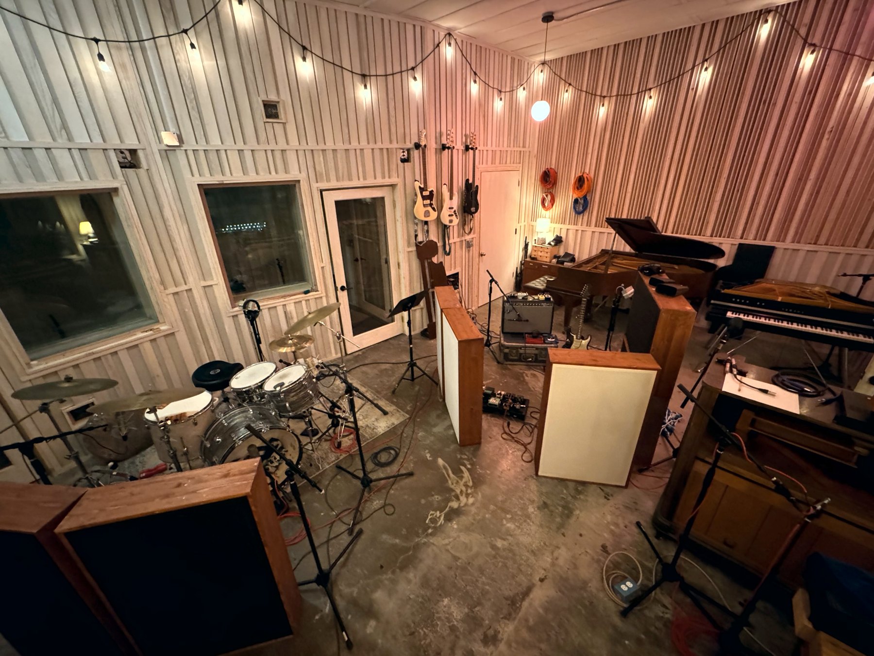 The Hotel Earth live room: drum kit, gobos, grand piano, CP-70 and guitars on the wall